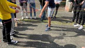 Jugendliche erleben Zusammenarbeit bei einer Gruppenaktivität im Freien. teamwork, mitwirkung, gruppenspiel, kooperation, gemeinschaft, aktivität, beteiligung, straße, seile, spiel