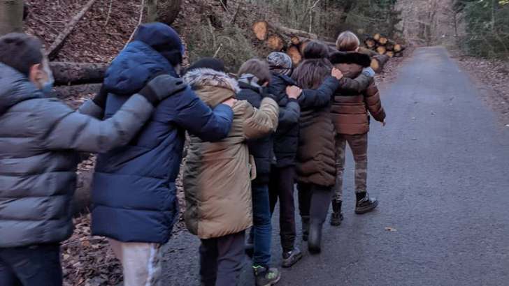  Kinder gehen im Wald hintereinander 